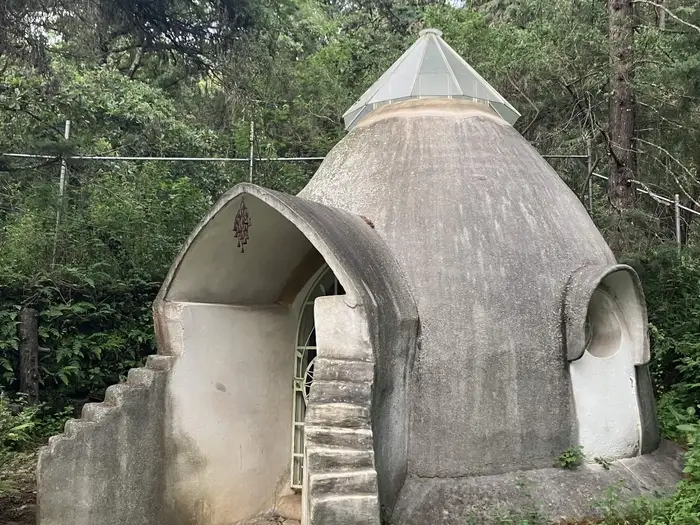 A rendered dome with an arched opening and an external stair curving up its side.